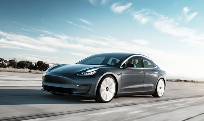 A dark gray Tesla Model 3 Performance, a compact high-performance electric luxury sedan.