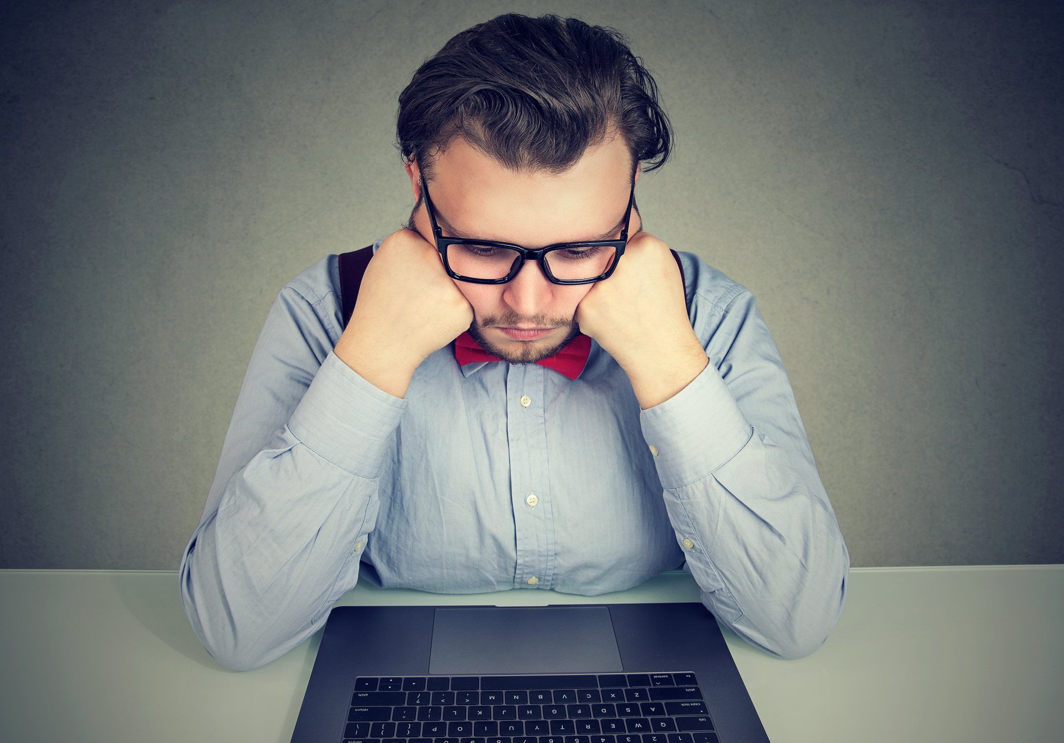 Man looking sad while sitting in front of a laptop.