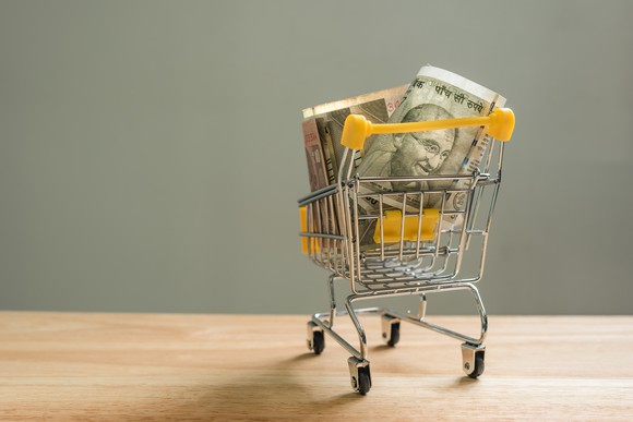 A mini shopping cart filled with rupees.
