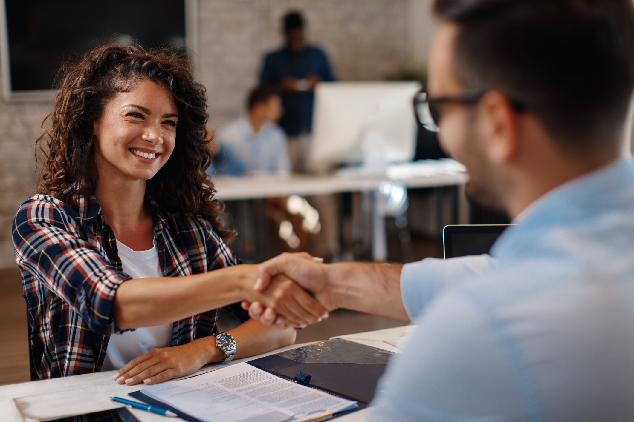 Smiling woman shaking hands with man across the table.
