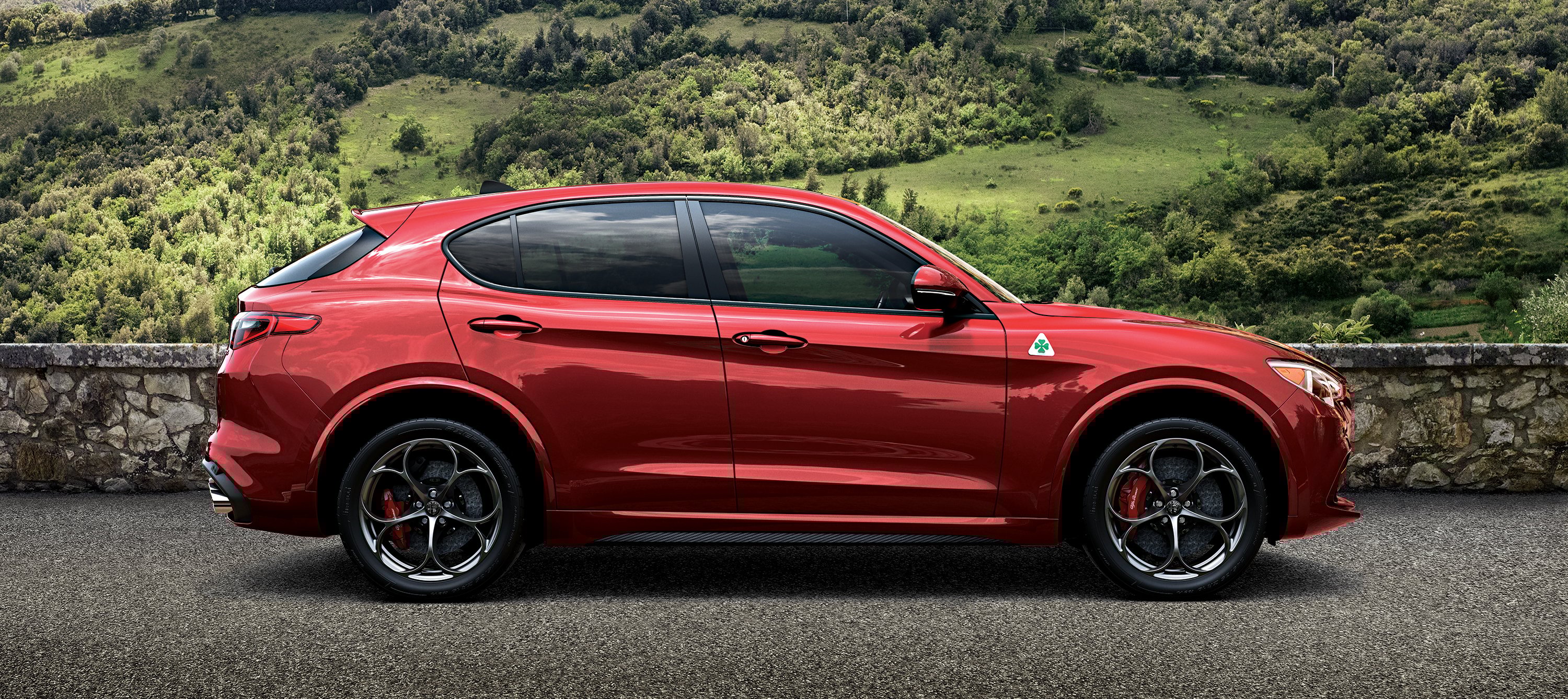 A red Alfa Romeo Stelvio, a high-performance 5-passenger luxury-sports crossover SUV.