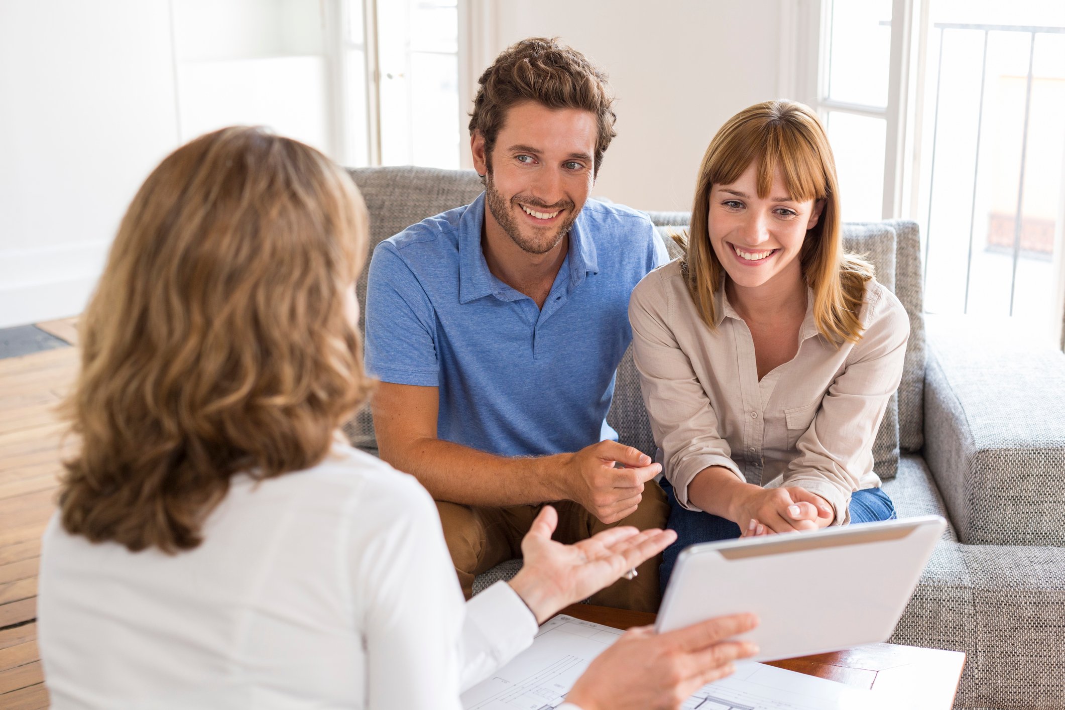 Couple sitting across from woman holding a tablet.