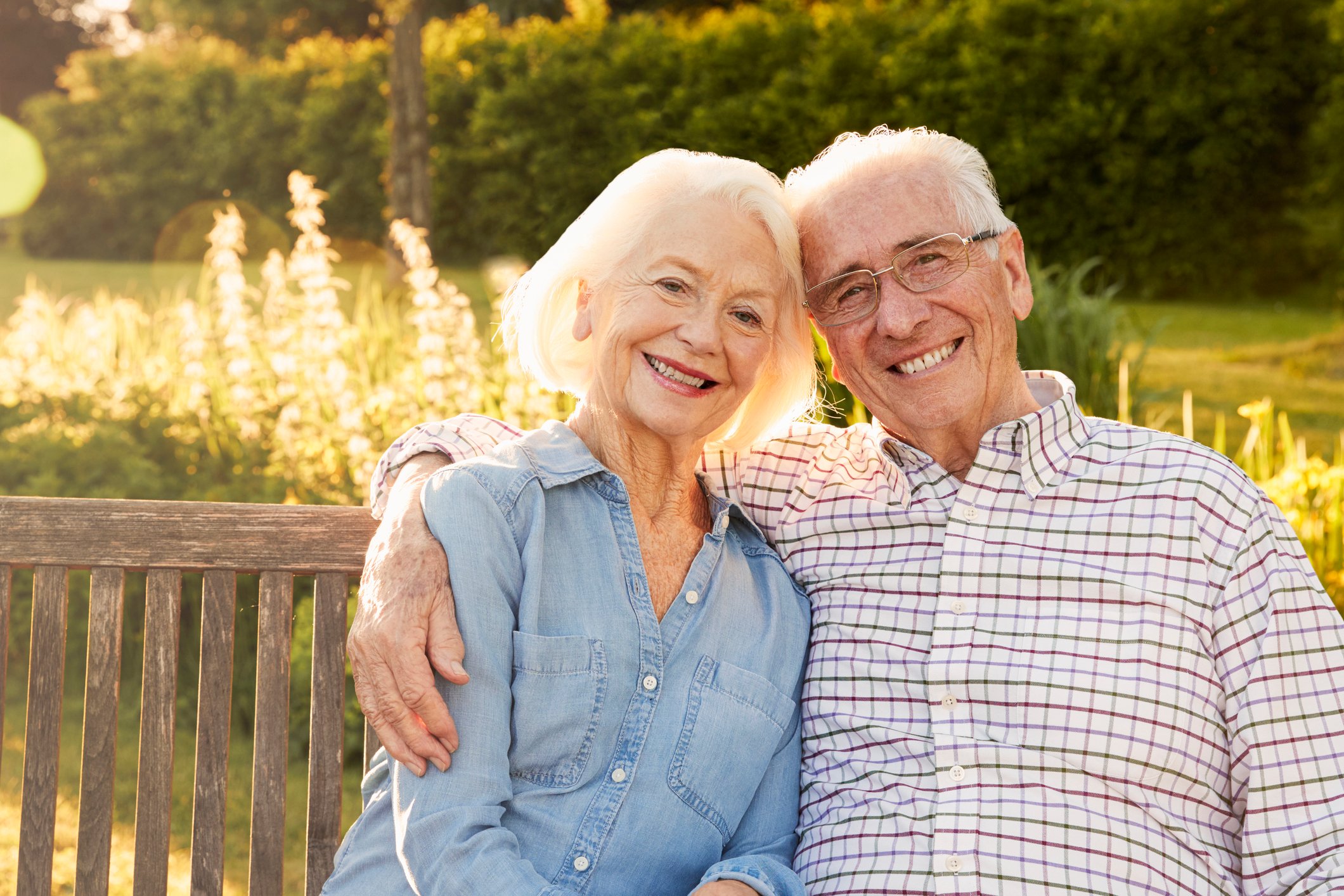 Smiling senior couple on bench outdoors.