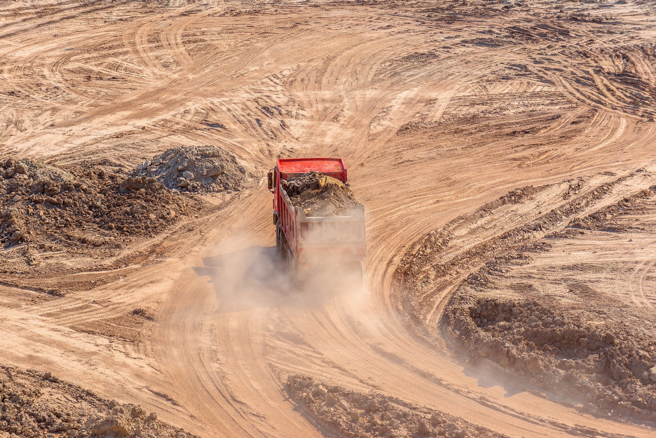 A mining truck driving on a dusty road.