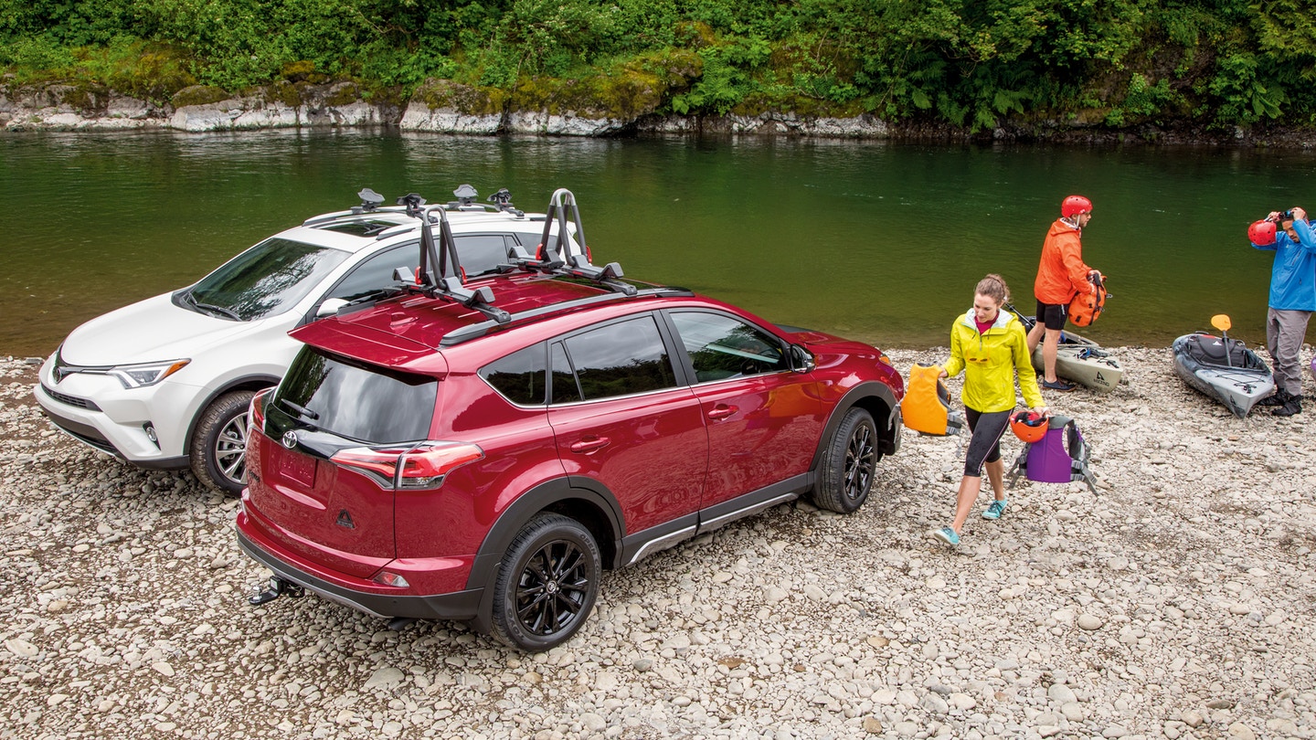 People three people next to a river with two kayaks and two Toyota RAV4s