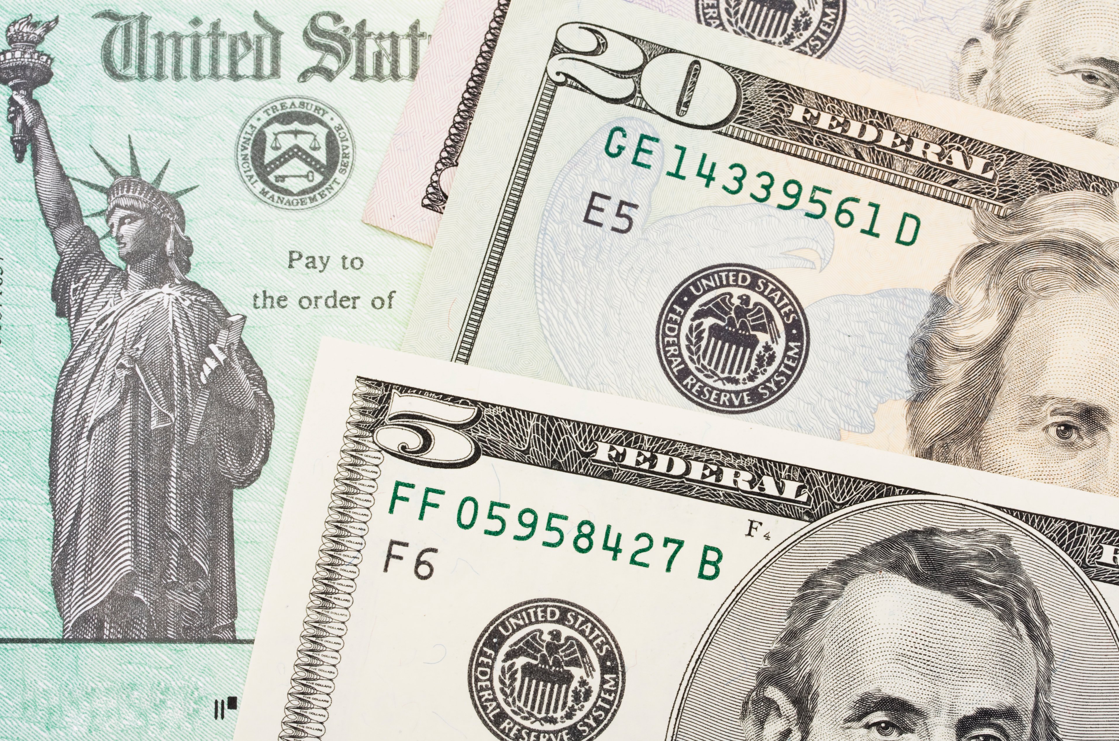 Money laying on top of a US Government check.