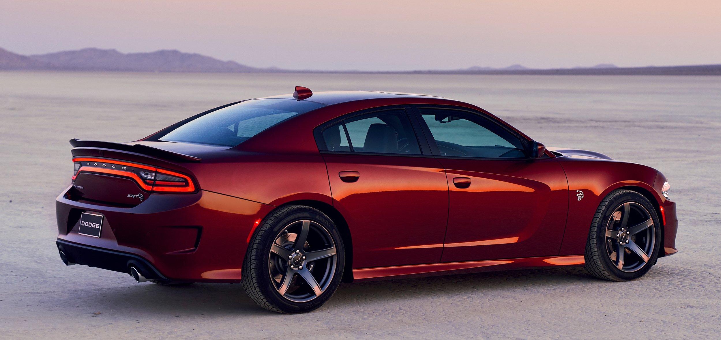 A dark red 2019 Dodge Charger SRT Hellcat, a full-size high-performance sedan, in a desert setting.