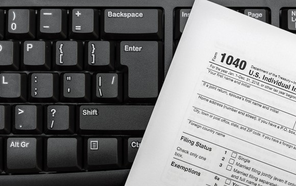 Tax Form 1040 resting on computer keyboard.