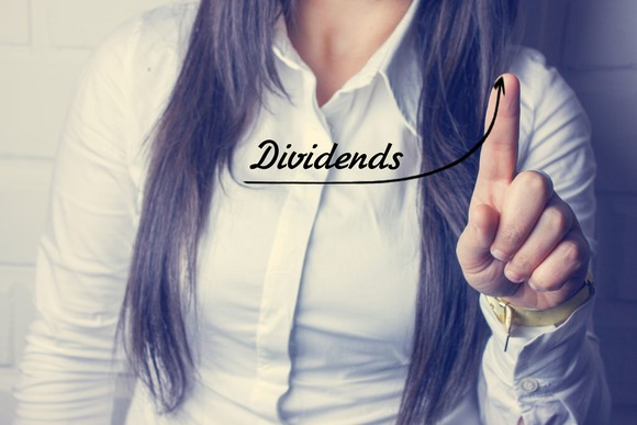 Woman pointing to the word dividends with an arrow beneath it curving up.