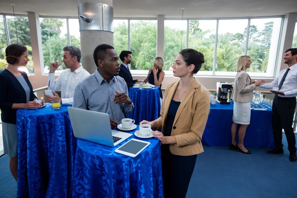 Adults congregating around tables, dressed professionally