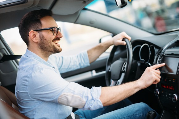 Man using touchscreen display in a car.