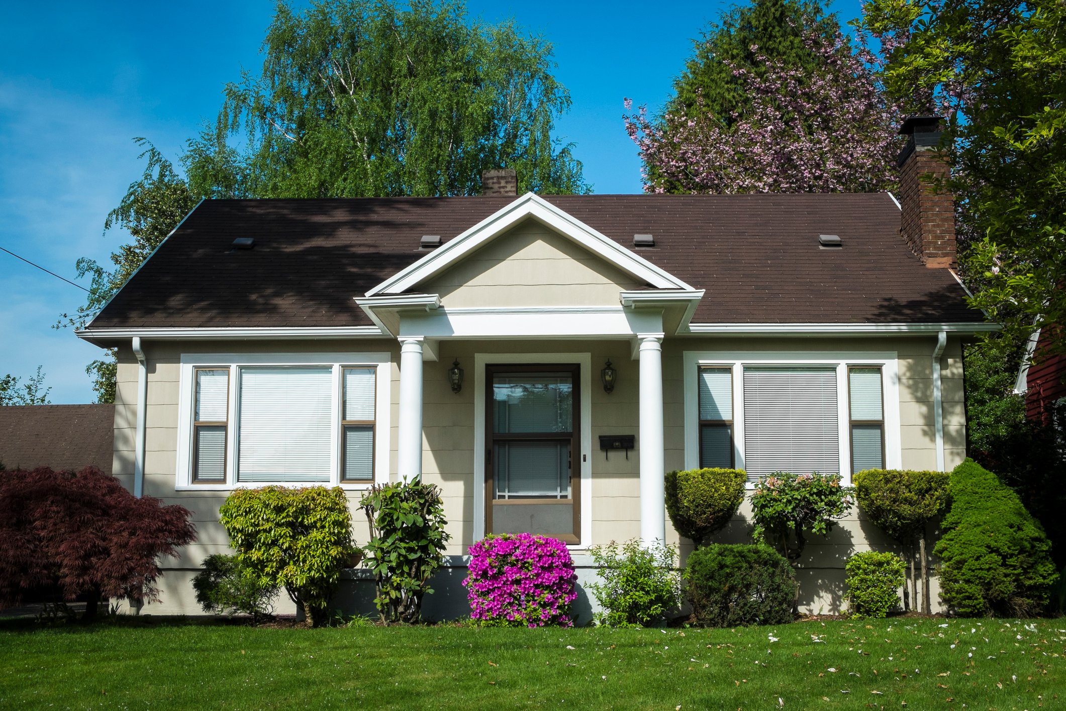 A small single-story house with landscaping, as seen from across the yard.