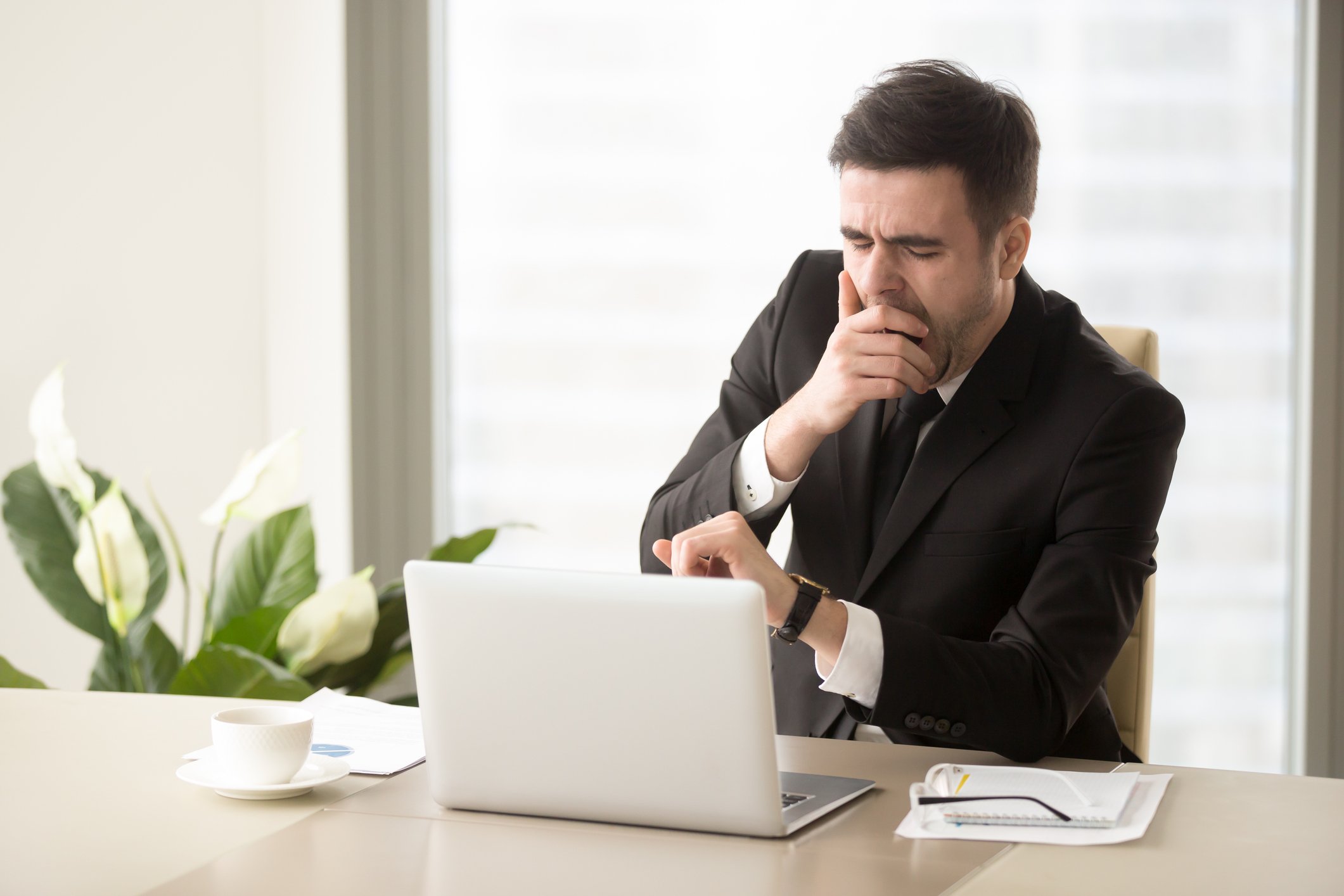 Man in suit yawning at desk