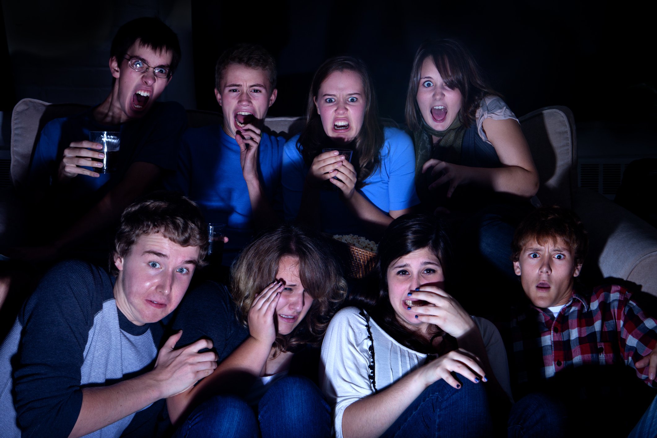 A group of people watch a horror movie on tv.