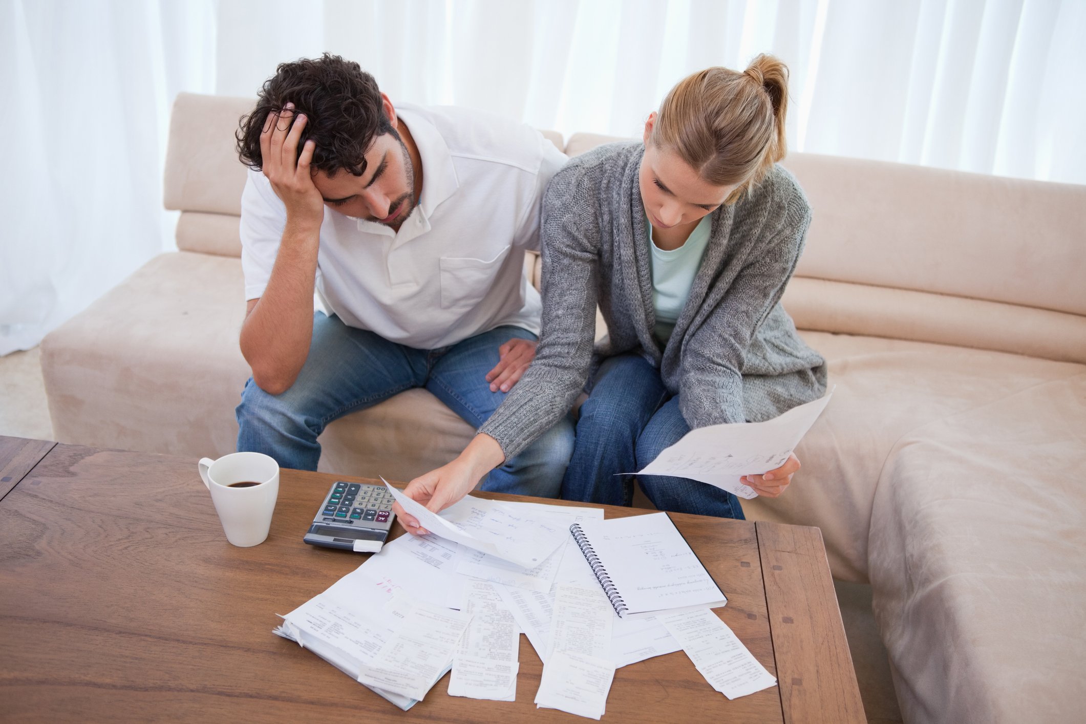 Man and woman sitting on couch with papers spread out on table in front of them