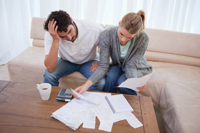 Man and woman sitting on couch with papers spread out on table in front of them