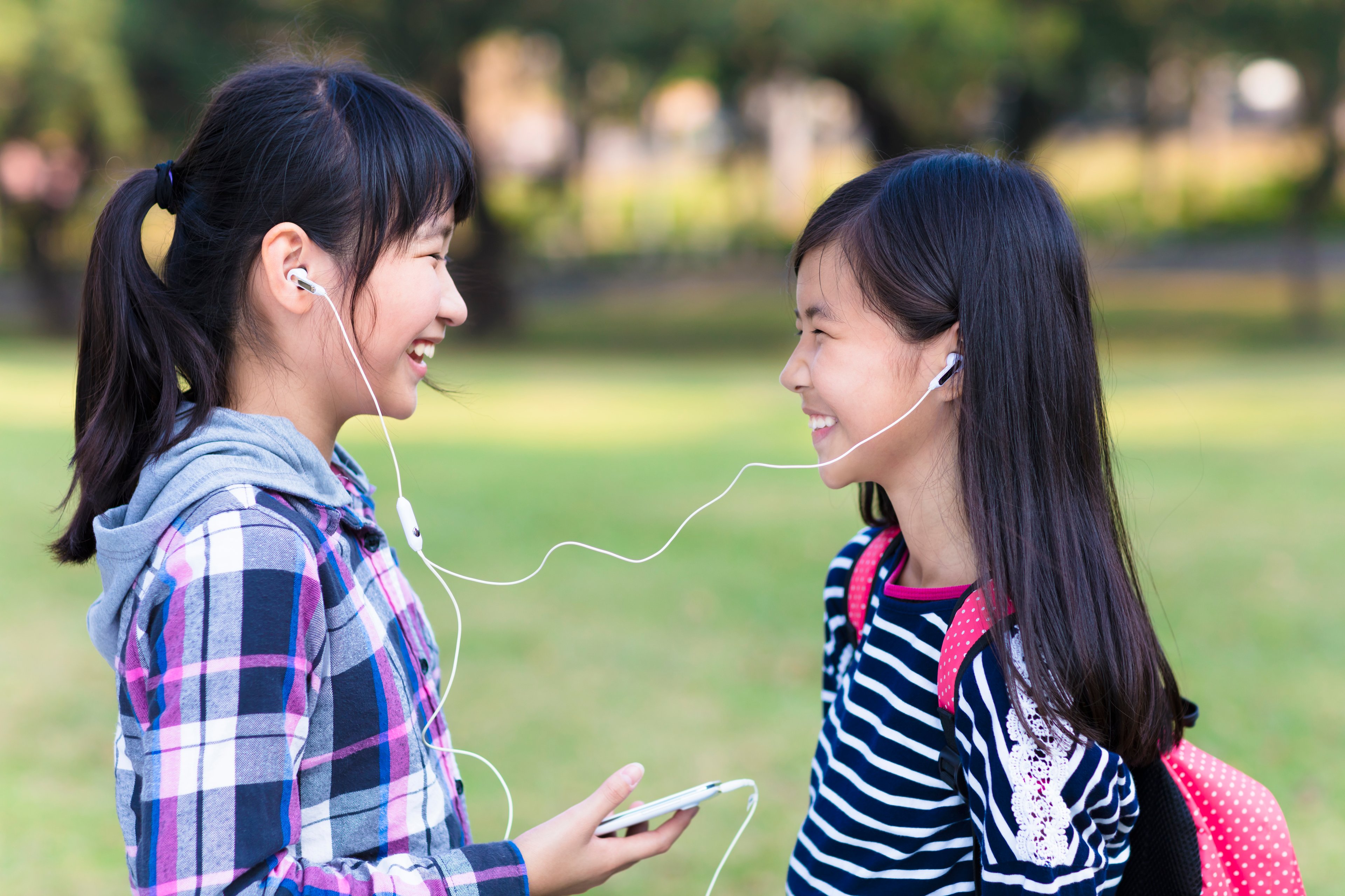 Two Asian girls listening to music on earbuds