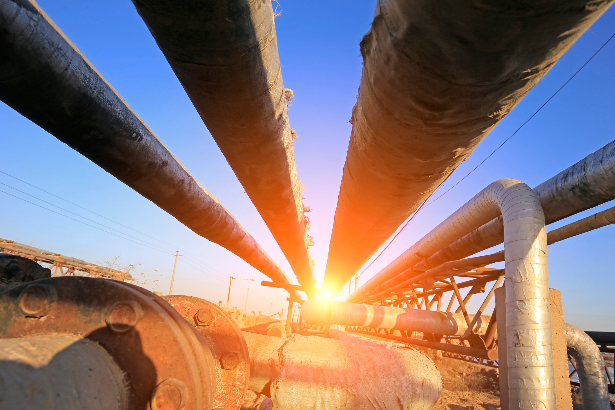 Several pipelines with the sun shining brightly beyond them.