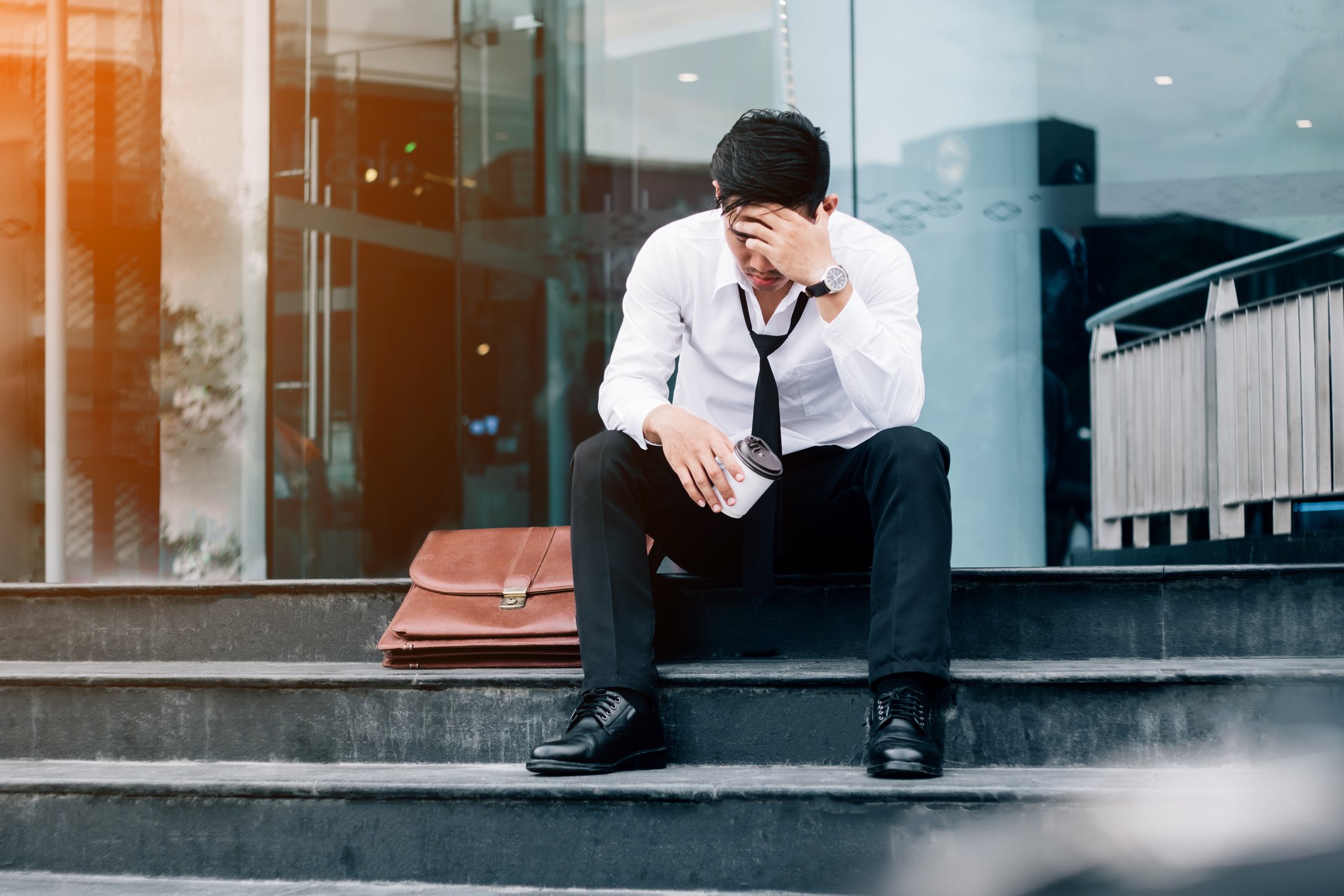 A man looks sad sitting on a staricase.