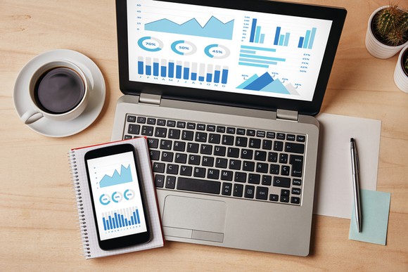 A view of a desk with a laptop, phone, coffee mug, and pencil.
