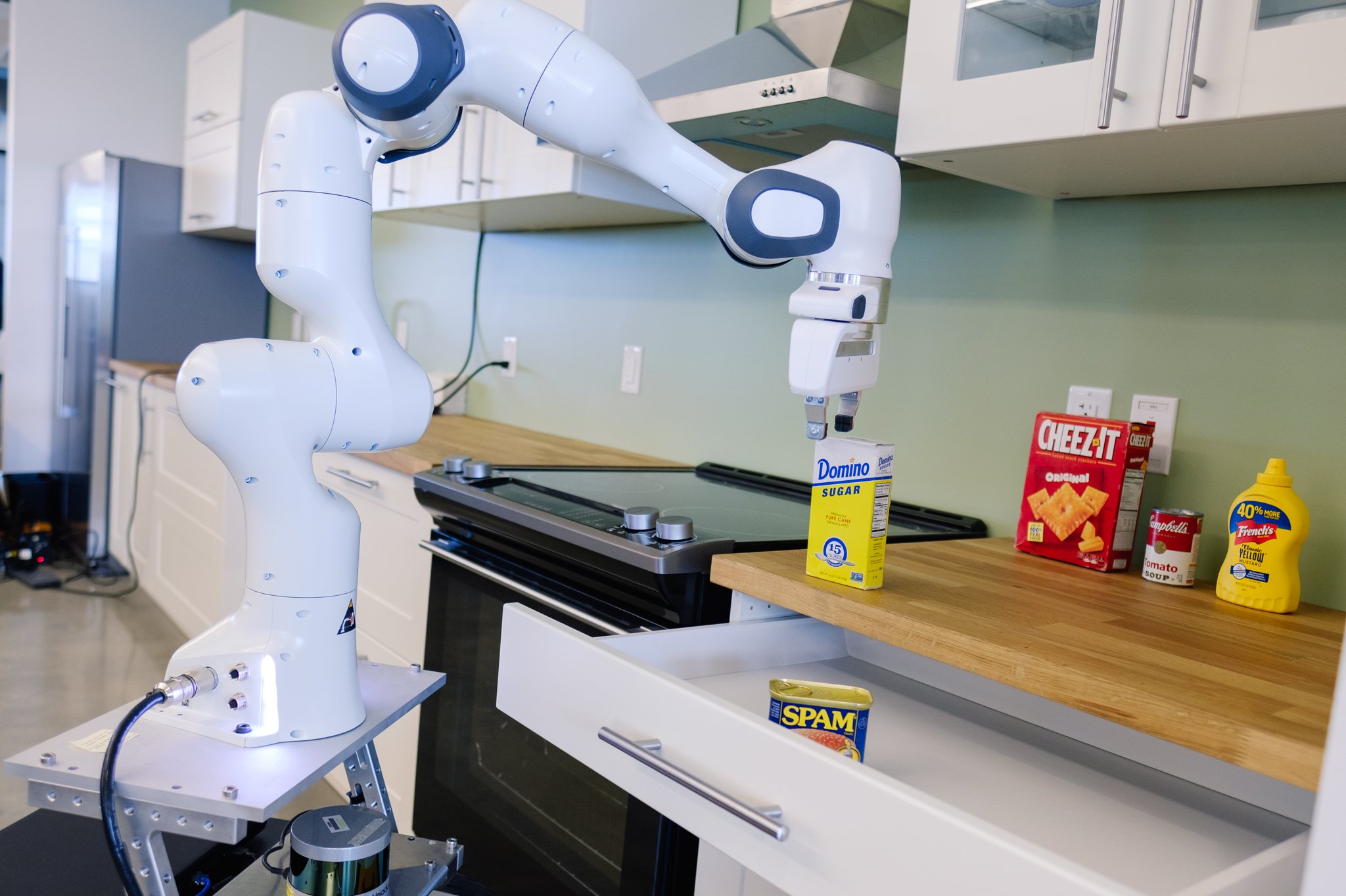 Robot arm working with food items in a kitchen.