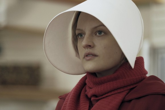A woman dressed in red, with a long white hood in a scene from Hulu's A Handmaid's Tale