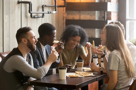 Group of young people eating and drinking coffee in a coffee shop.