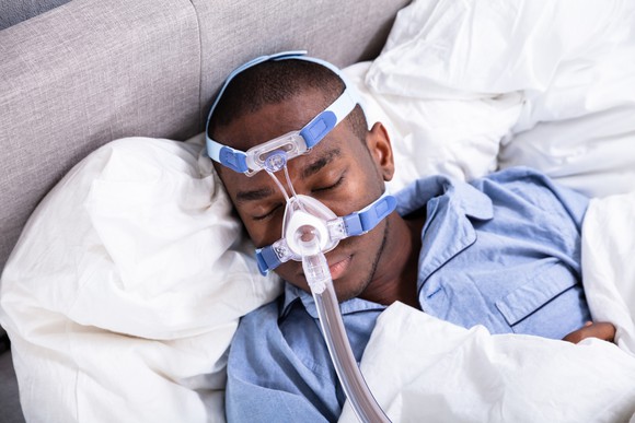 Man sleeping in bed with CPAP machine on his face