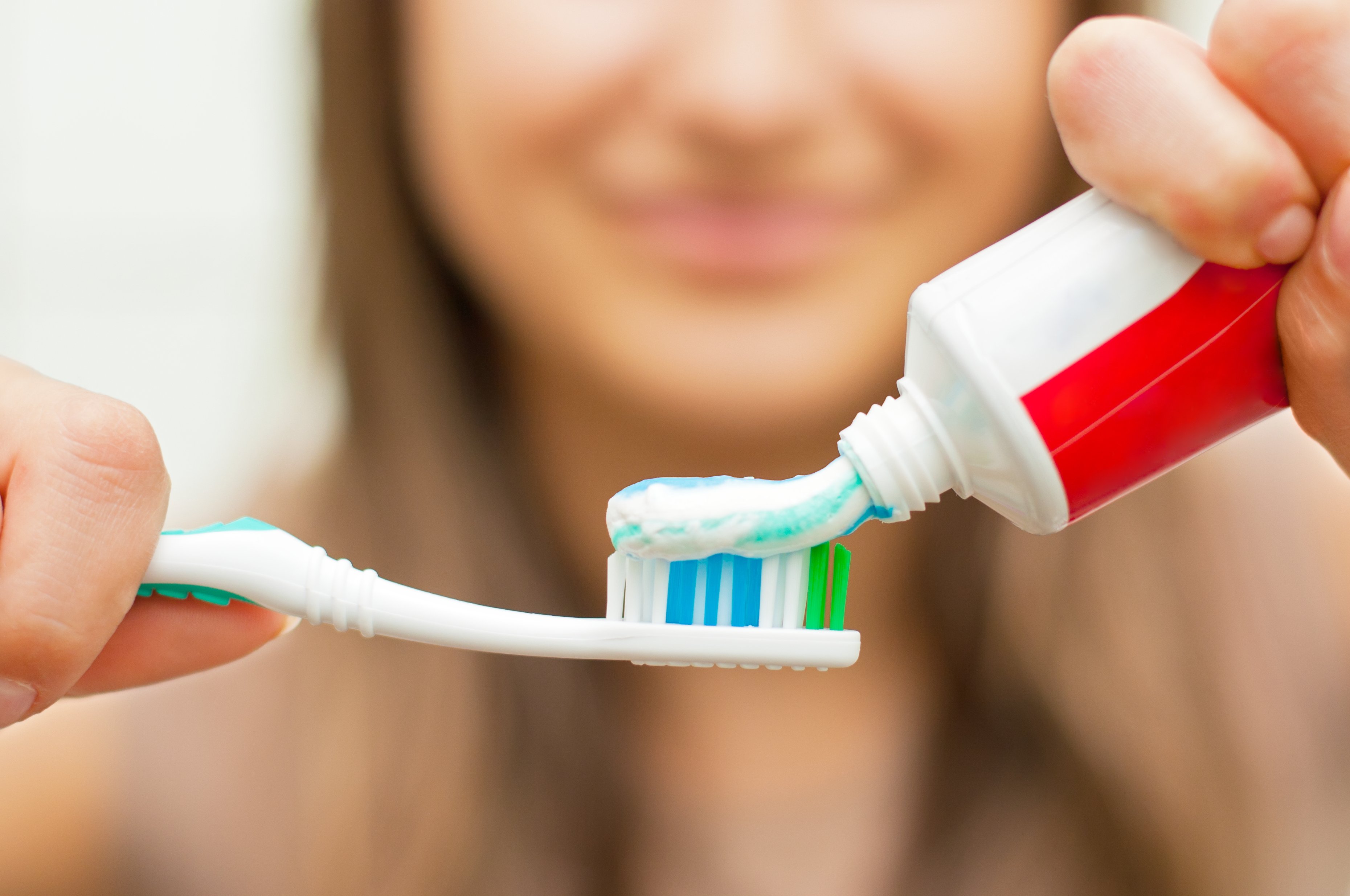 A woman applies toothpaste to a toothbrush.
