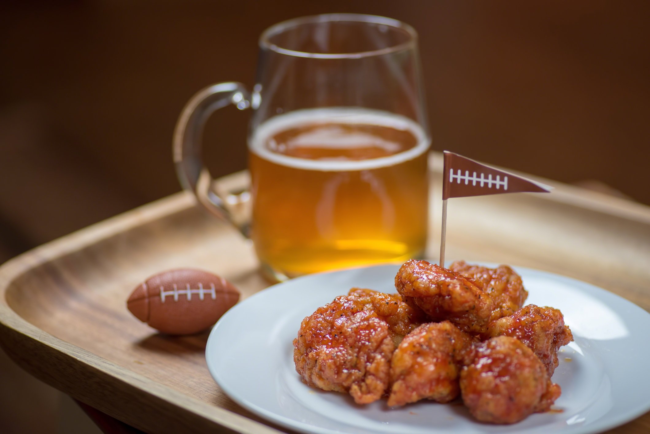 Wings and beer are next to a tiny football.