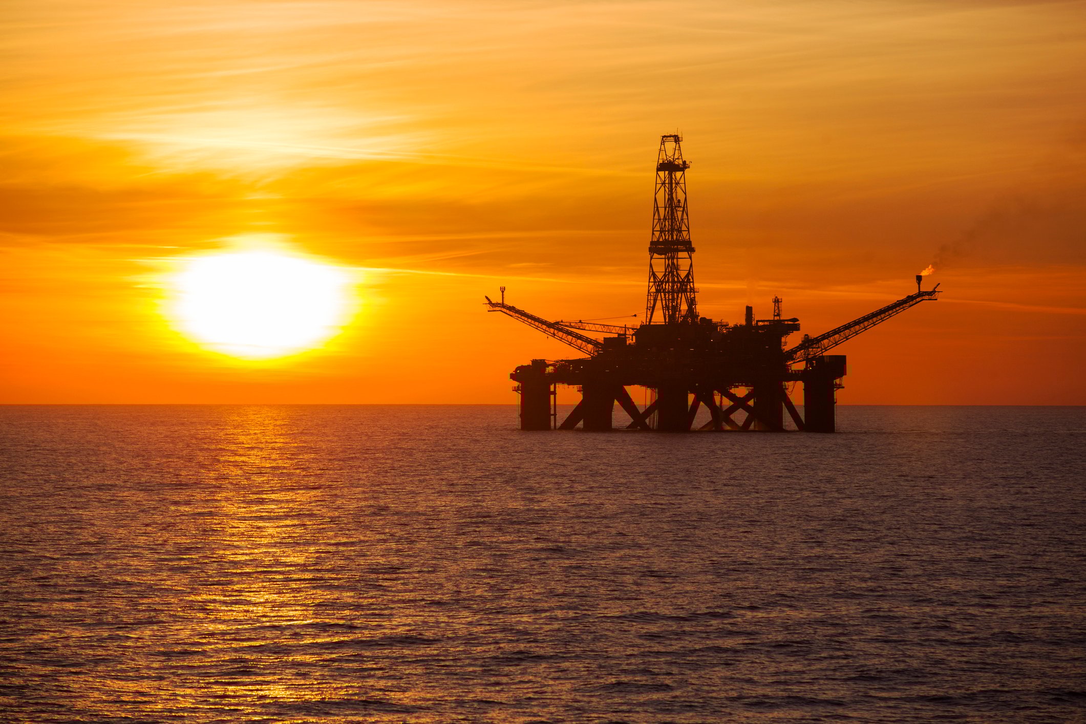An offshore oil rig at sunset.
