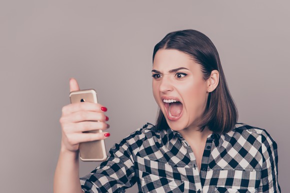 An angry woman screams at her phone.