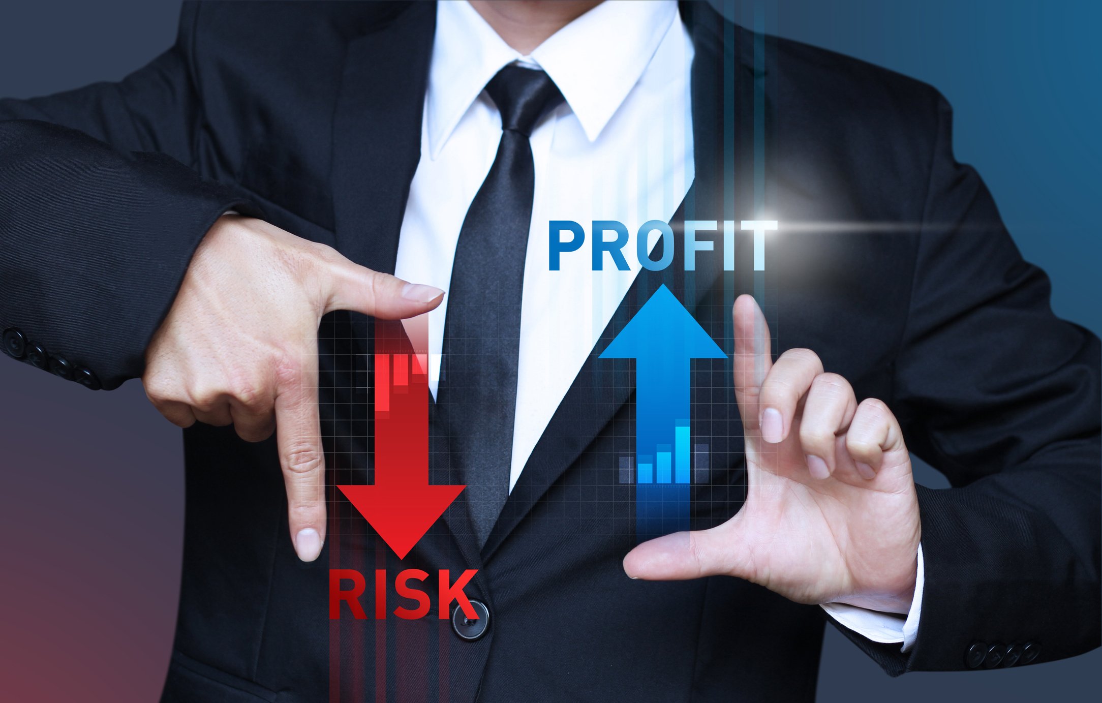 A man in a suit holding his hands out, framing the words "RISK" with an arrow pointing down and "PROFIT" with an arrow pointing up