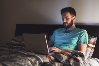 man on laptop in bed_GettyImages-855977576