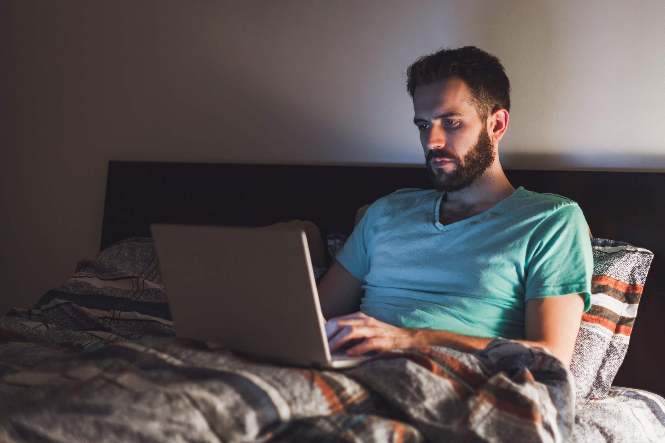 Man using laptop in bed.