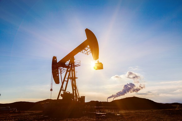 An oil pump with the sun glowing behind it.