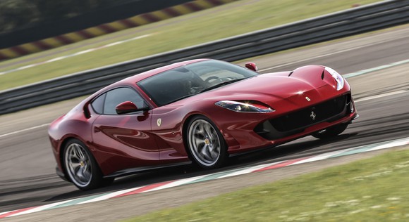 A red 2019 Ferrari 812 Superfast, a two-seat front-engined exotic sports car, at speed on a race track. 