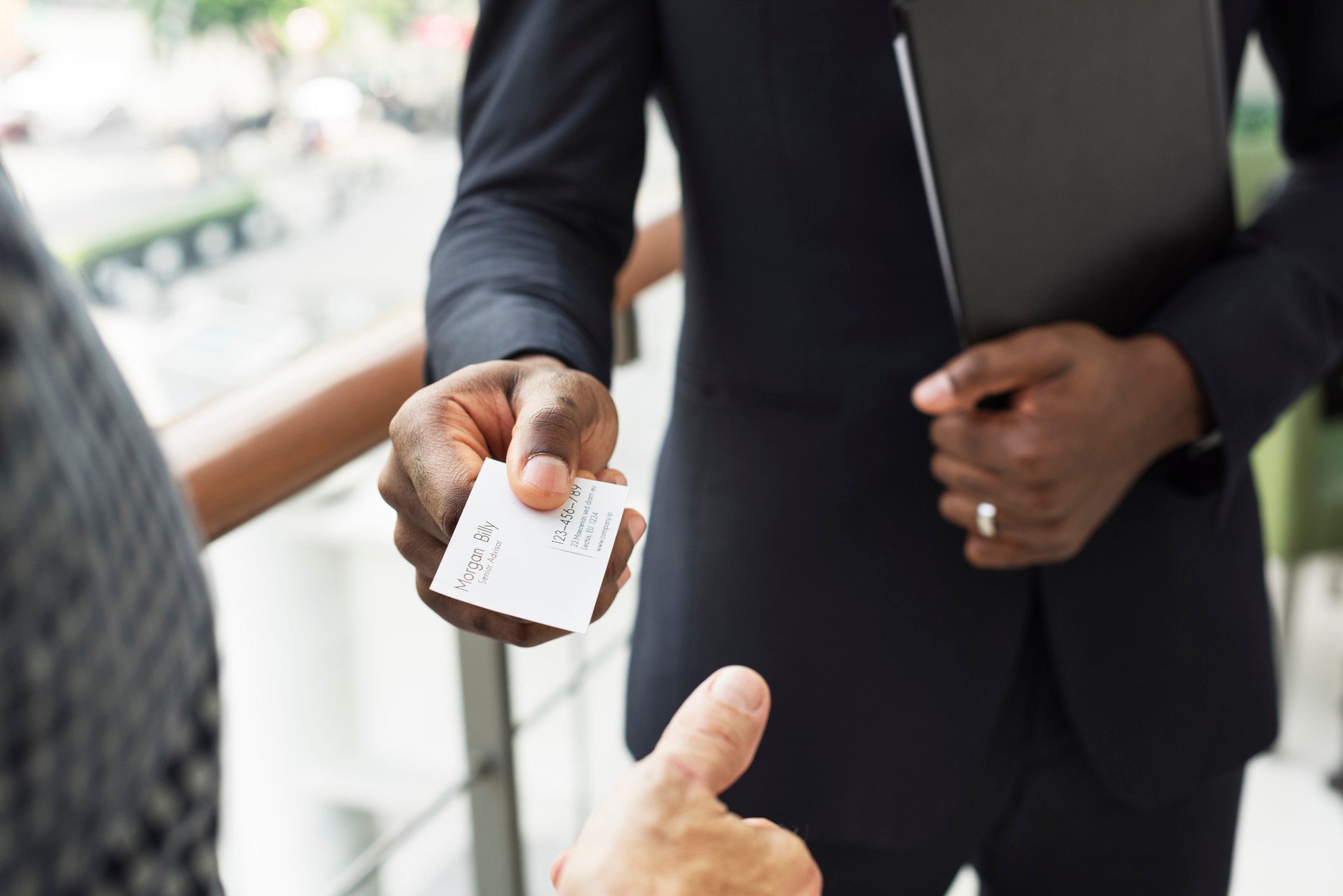 Man in suit handing another person his business card.