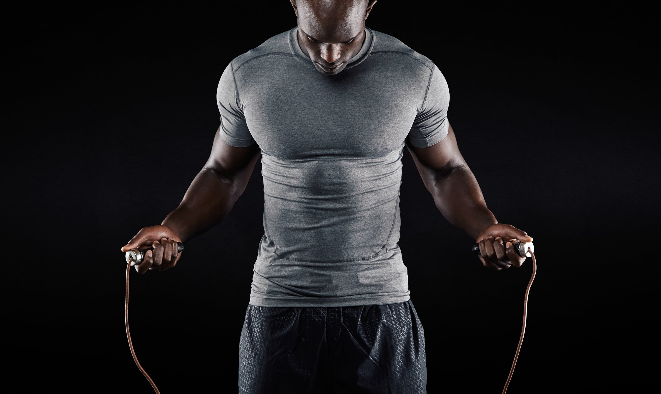 A very fit and muscular man jumping rope.