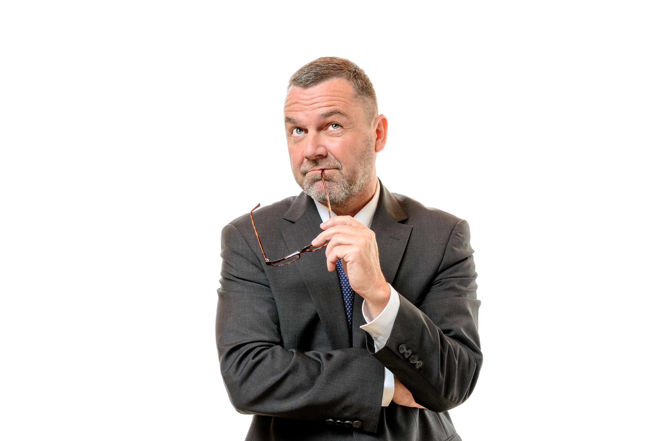 A man in a suit looks up, the bow of his glasses touches his lips.