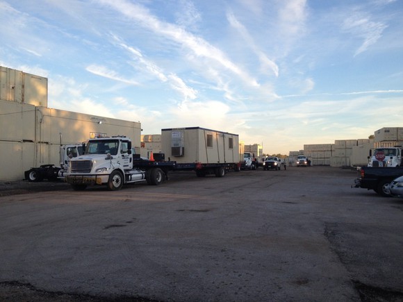 Parking lot with trucks and several Mobile Mini storage containers.