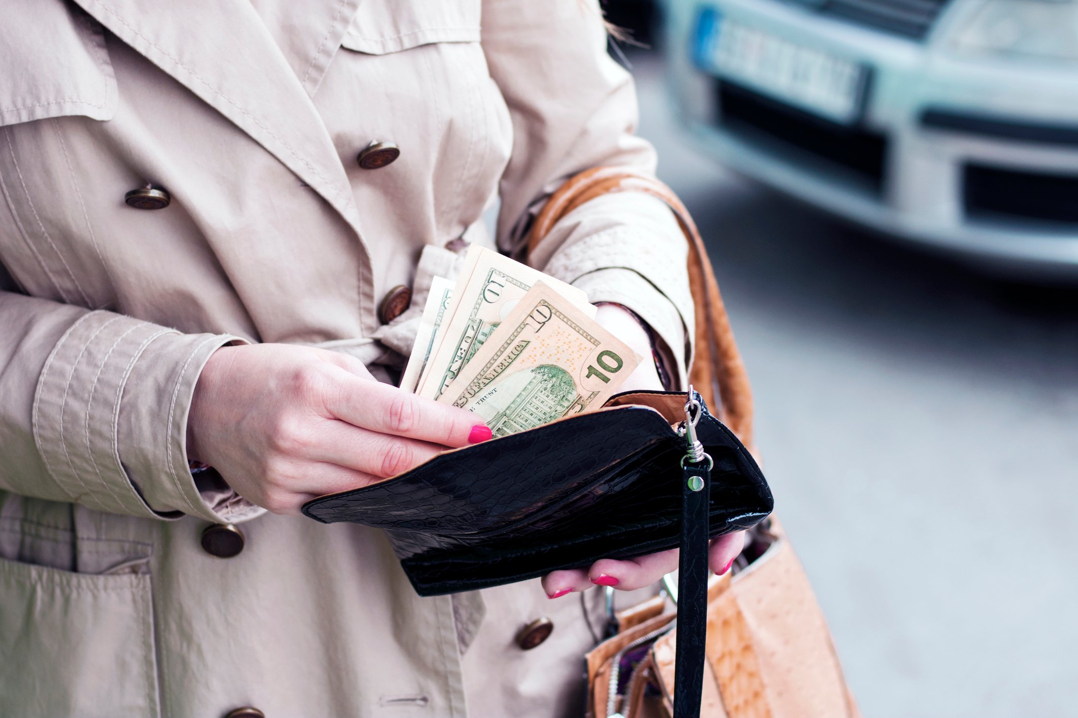 A woman takes money from a wallet.