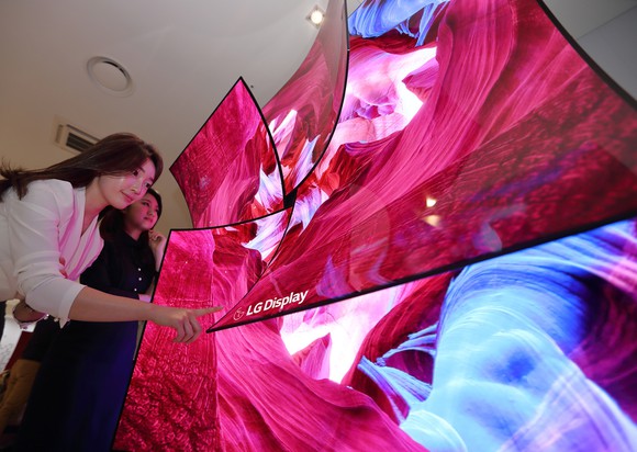 Two people near a showcase of curved displays from LG Display.