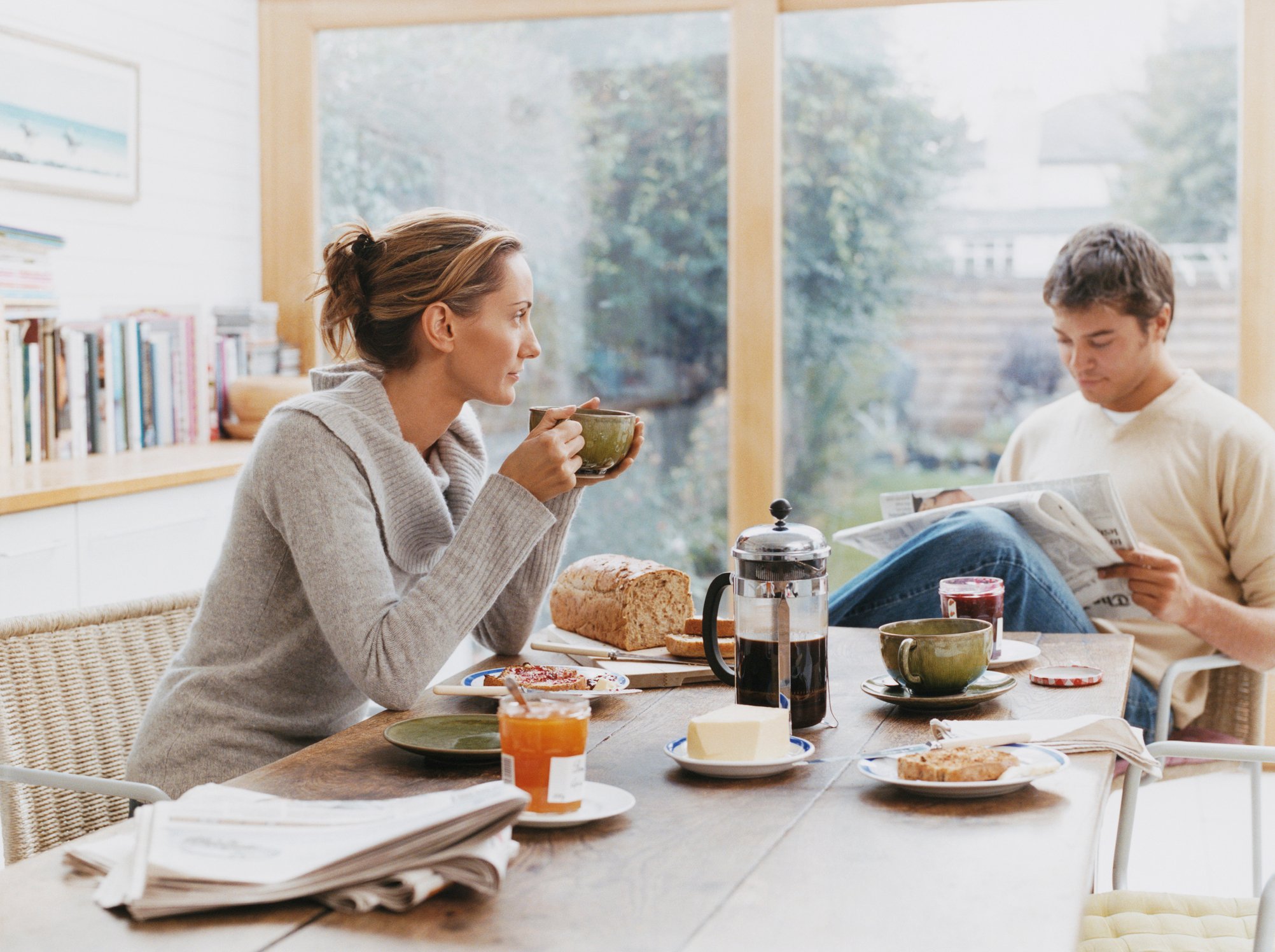 A young couple reads the daily paper at the breakfast table.