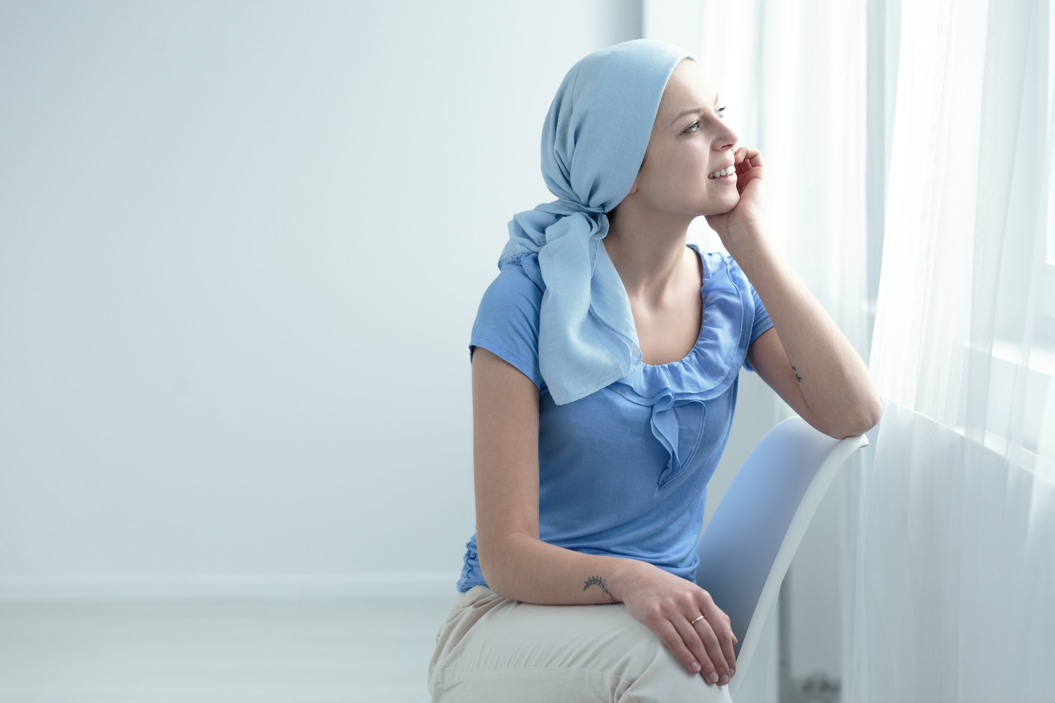 Female cancer patient staring out of a window in an all-white room