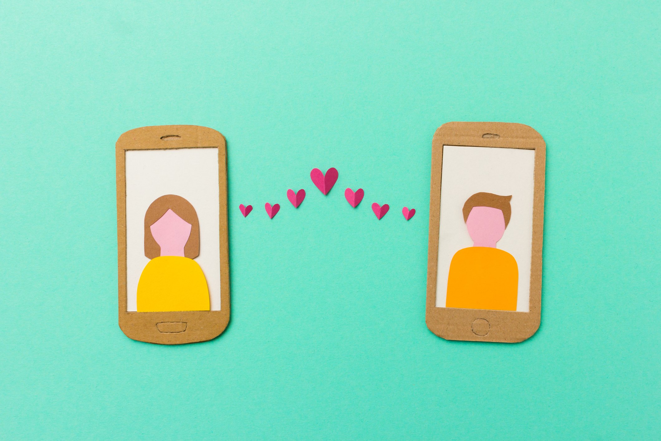 A man and a woman displayed on mobile phones, connected by hearts.