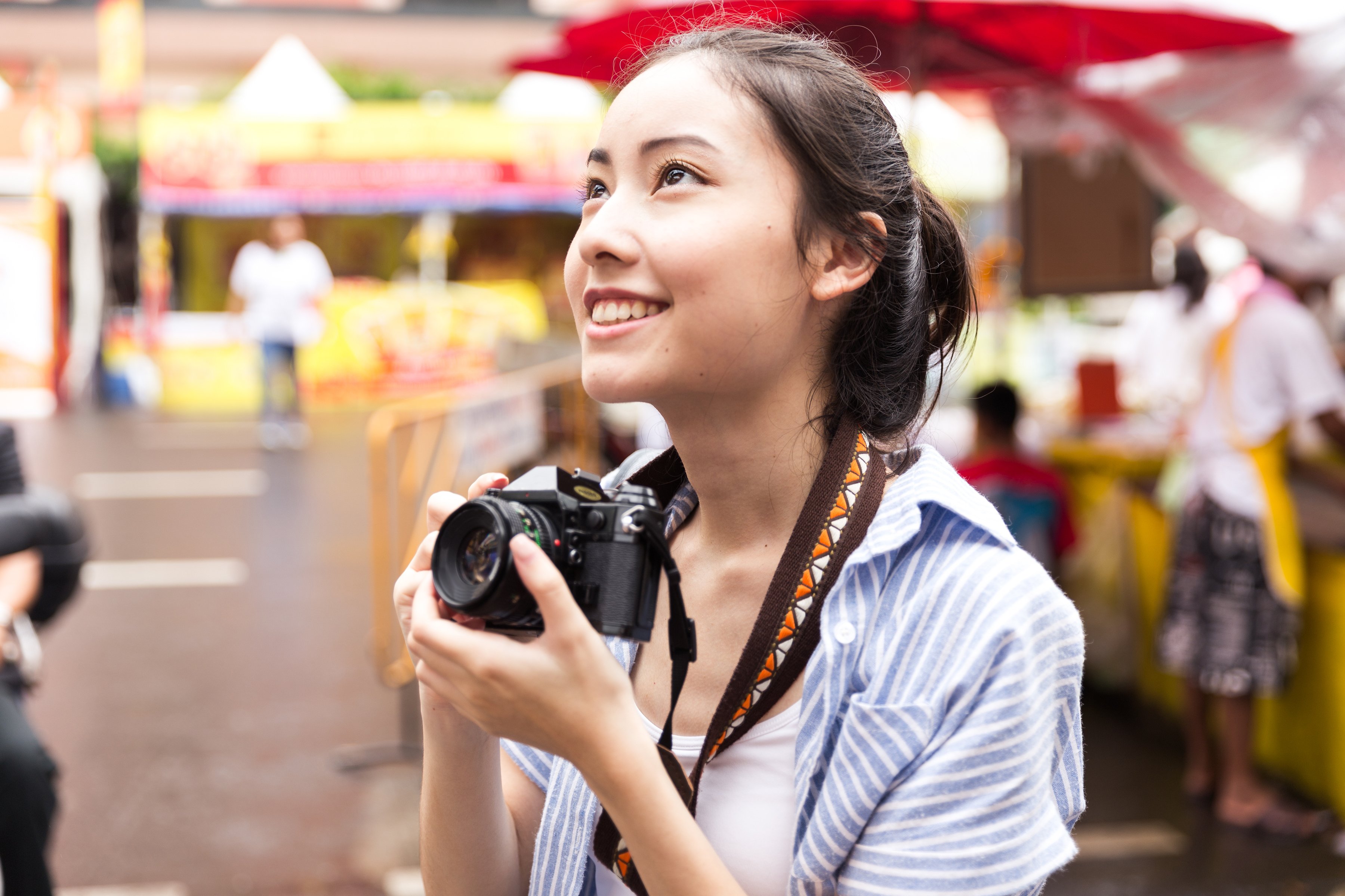 A Chinese woman holds a camera around her neck.