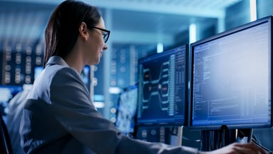 Woman sitting in front of computer screens