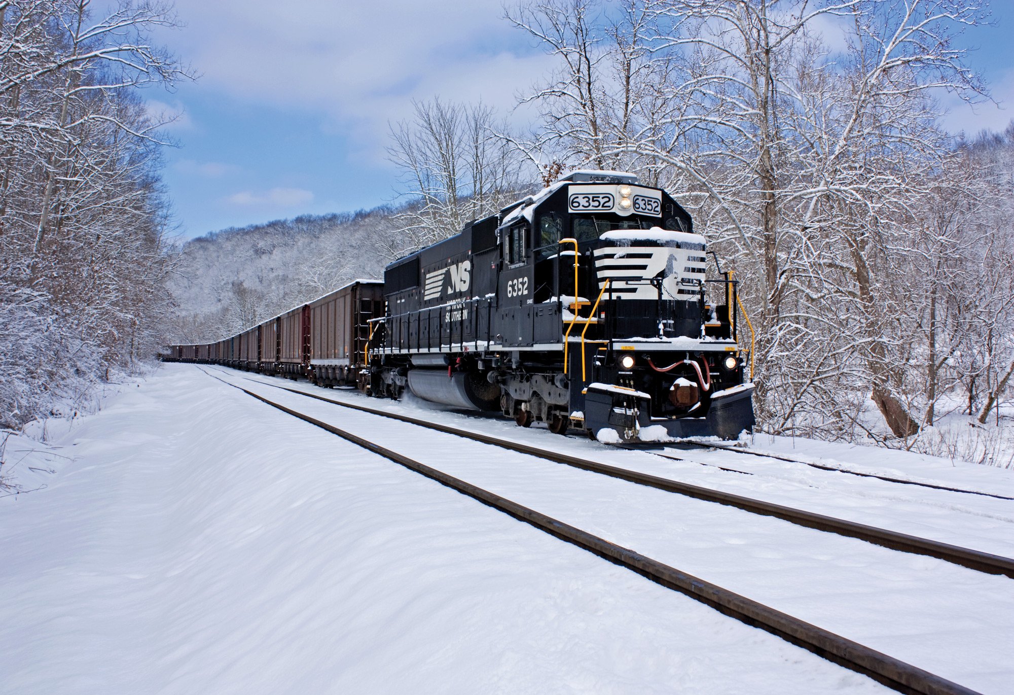 A Norfolk Southern engine navigating through a snowy landscape.