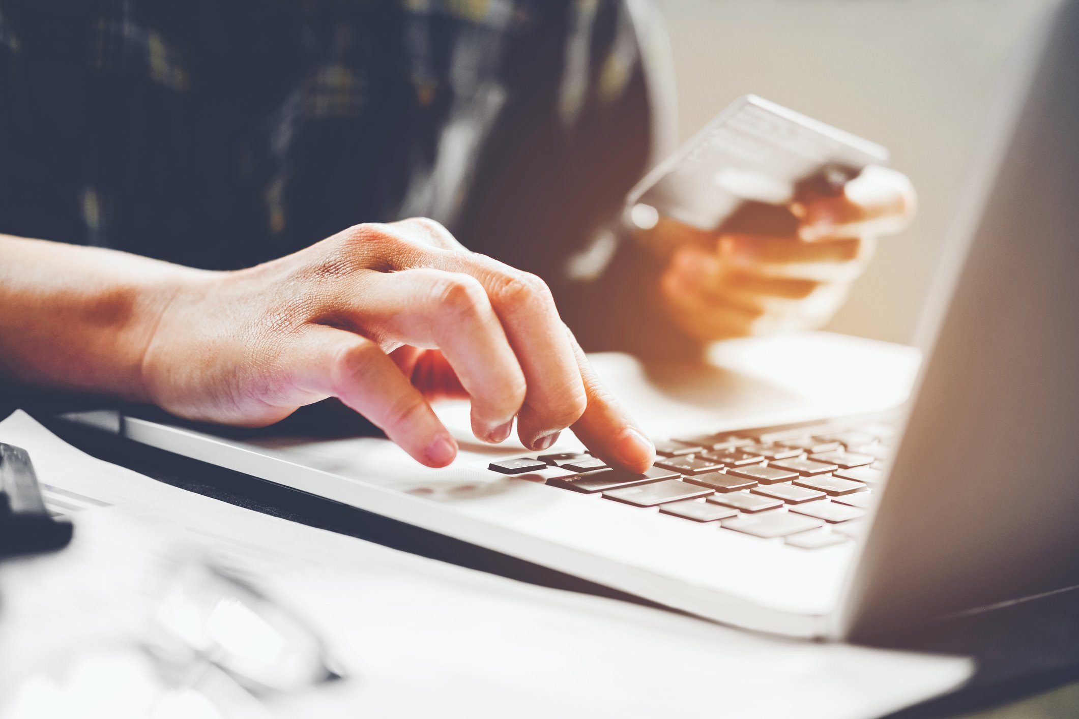 A man uses his credit card to make a purchase on a laptop.
